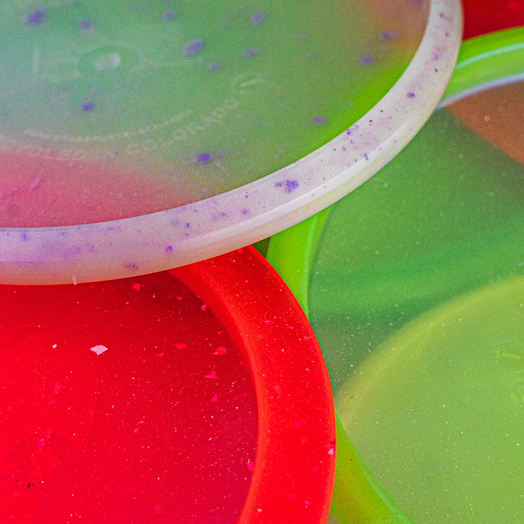 Closeup of 3 recycled disc golf discs sustainable trash panda