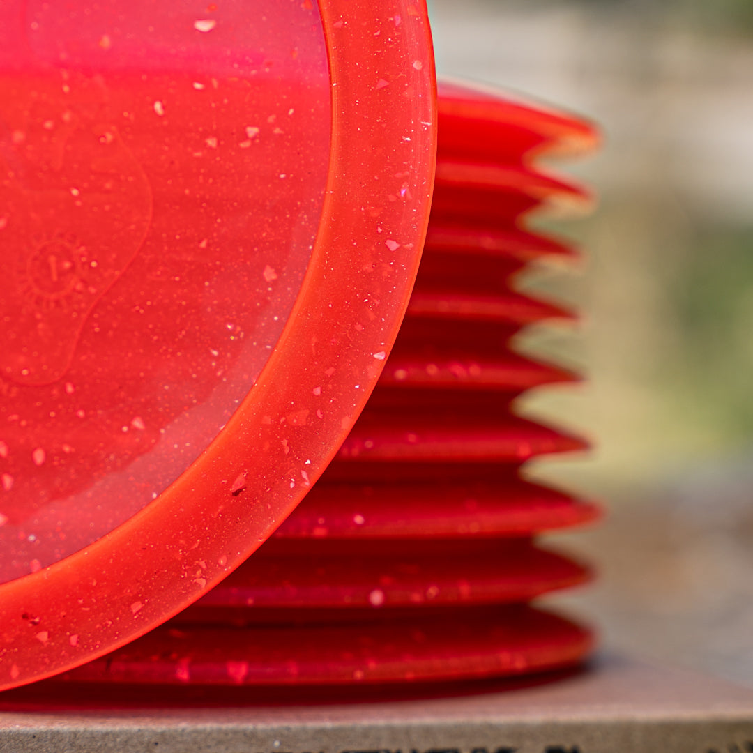 Closeup shot of the red Trash Panda Phone Case Ozone disc golf fairway driver made from recycled plastic