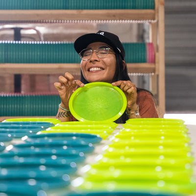 Maria Oliva smiling with her Signature Series Trash Panda Dune midrange disc golf disc