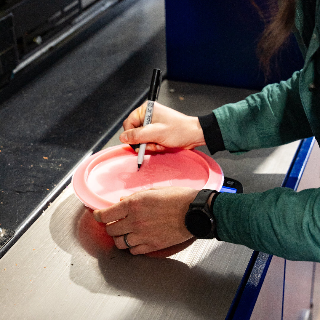 erika writing the weight on a disc golf disc